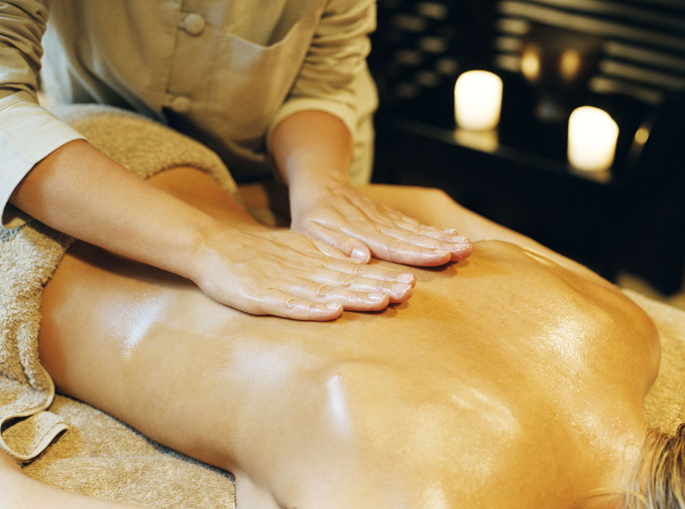 Hands applying a relaxing oil massage to the back